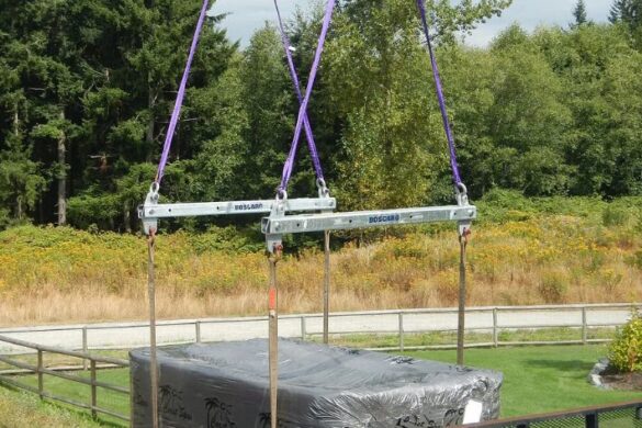 Crane spreader bar lifting large construction materials with even load distribution on a jobsite